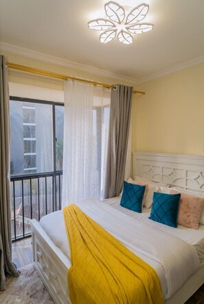 Ein Schlafzimmer mit Bett, Vorhängen, einem Balkon und einer Deckenleuchte.