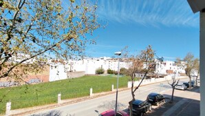 A street view with parked cars, a grassy area, and buildings in the background. - Aura Conil 32326 in Conil de la Frontera (Conil de la Frontera)
