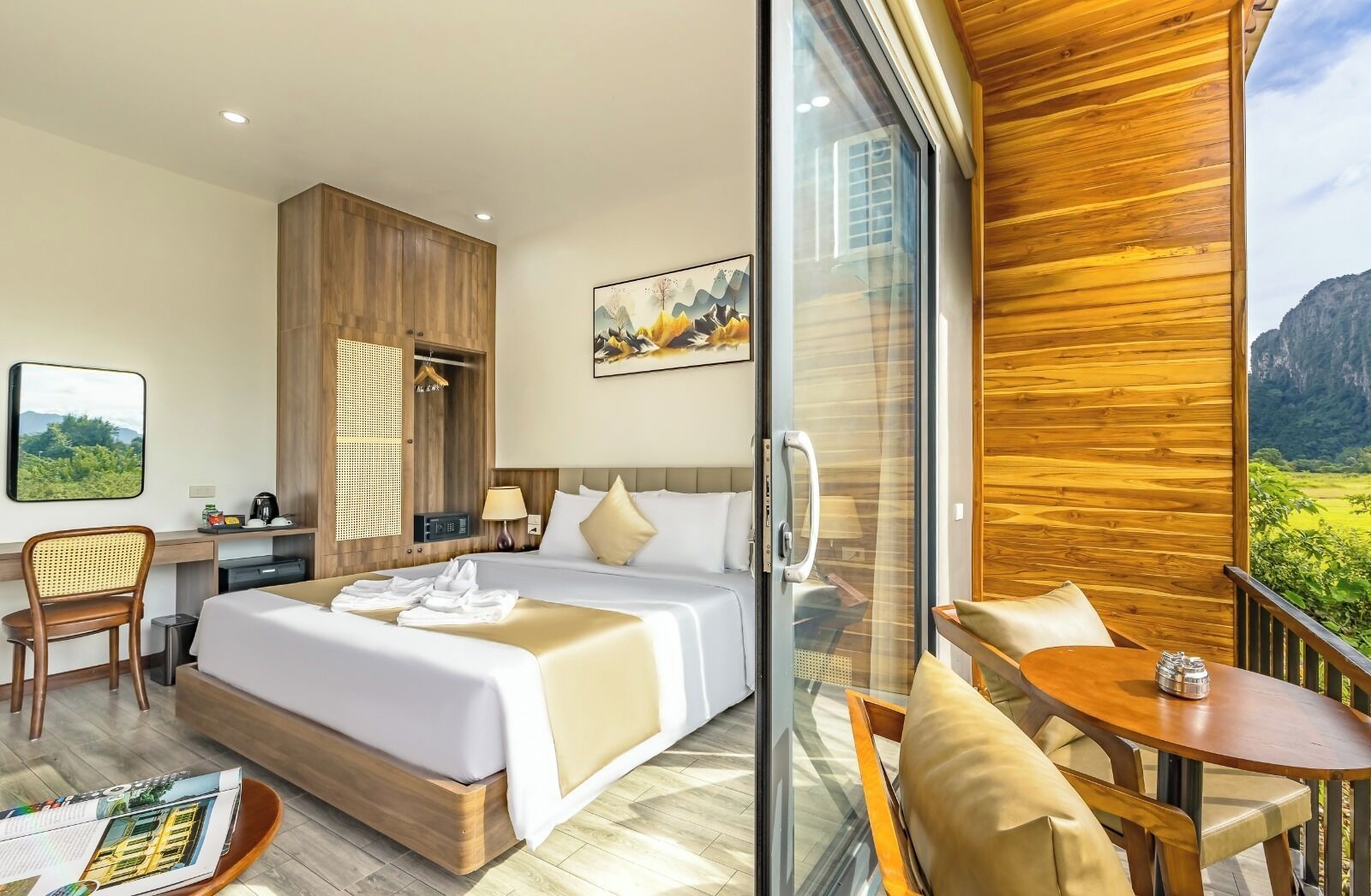 Habitación de hotel con cama, escritorio, silla, mesa y balcón con vistas.