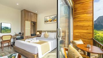 Habitación de hotel con cama, escritorio, silla, mesa y balcón con vistas.