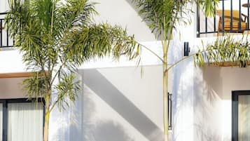 A modern building with a pool, palm trees, and a balcony.