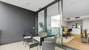 A modern living room with a glass wall, a dining area, and a kitchen. - Walk to The Gabba | Stylish with Rooftop Views (Woolloongabba)