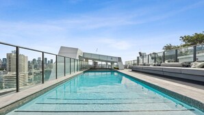 A rooftop pool with a city view, glass railings, and modern seating. - Walk to The Gabba | Stylish with Rooftop Views (Woolloongabba)