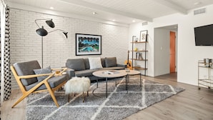 A modern living room with a sofa, armchair, coffee table, and a mounted TV.