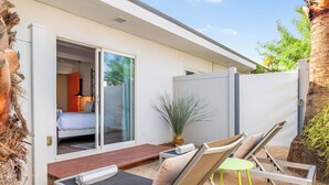 Een moderne buitenlounge met een pooltafel, lounge fauteuils en een schuifdeur die leidt naar een slaapkamer.