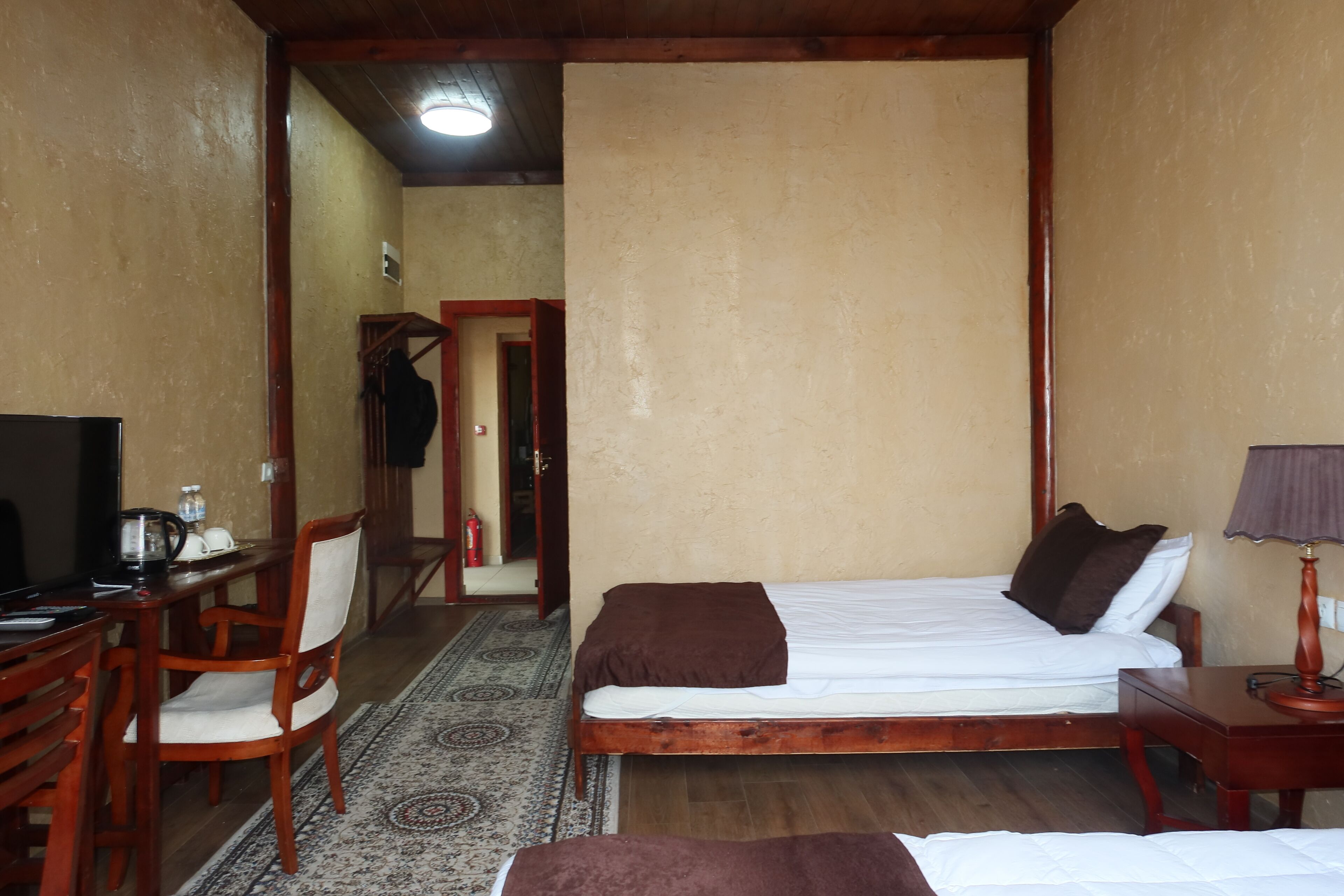 Una habitación con una cama, un escritorio con silla, un televisor y una lámpara.