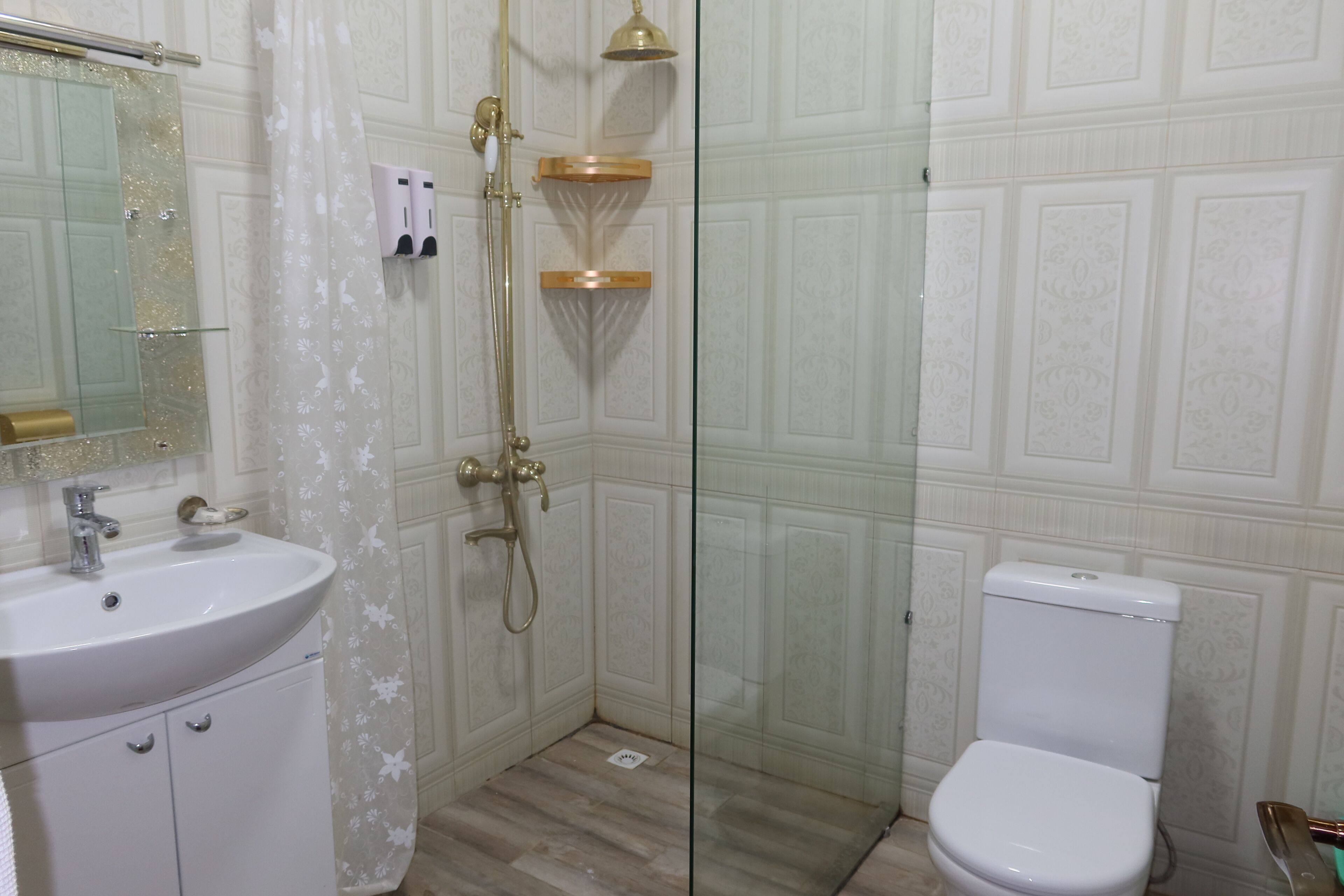 Een badkamer met een witte wastafel, een douchecabine van glas en een wit toilet.
