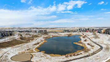 A residential area with multiple apartment buildings, a large pond, and a clear sky.
