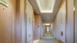 A hotel corridor with wooden paneling, numbered doors, and signs indicating room rates. - Vienna Sleep International Hotel (Shenzhen)