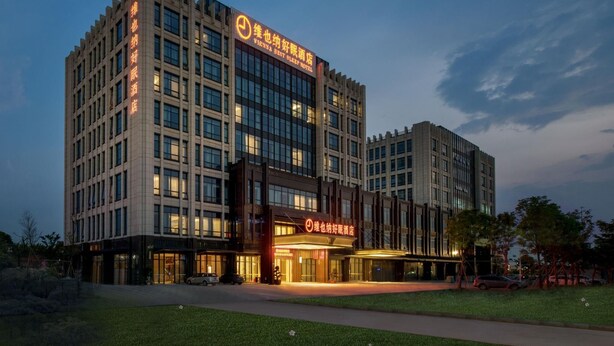 A multi-story hotel with a prominent entrance and signage. - Vienna Sleep International Hotel (Shenzhen)