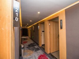 Un pasillo con paredes de madera, puertas numeradas y una alfombra estampada.