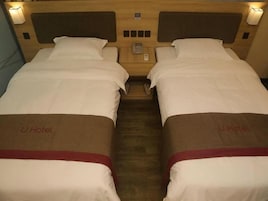 Una cama doble con cabecera, una mesita de noche con lámpara y un teléfono.