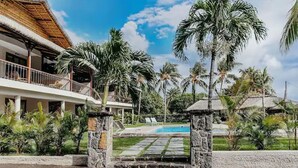 Un resort con piscina, palmeras y un edificio de techo de paja.