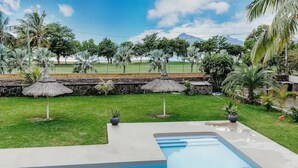 Una piscina con un muro de piedra y palmeras al fondo.