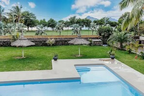 Una piscina con un muro de piedra y palmeras al fondo.