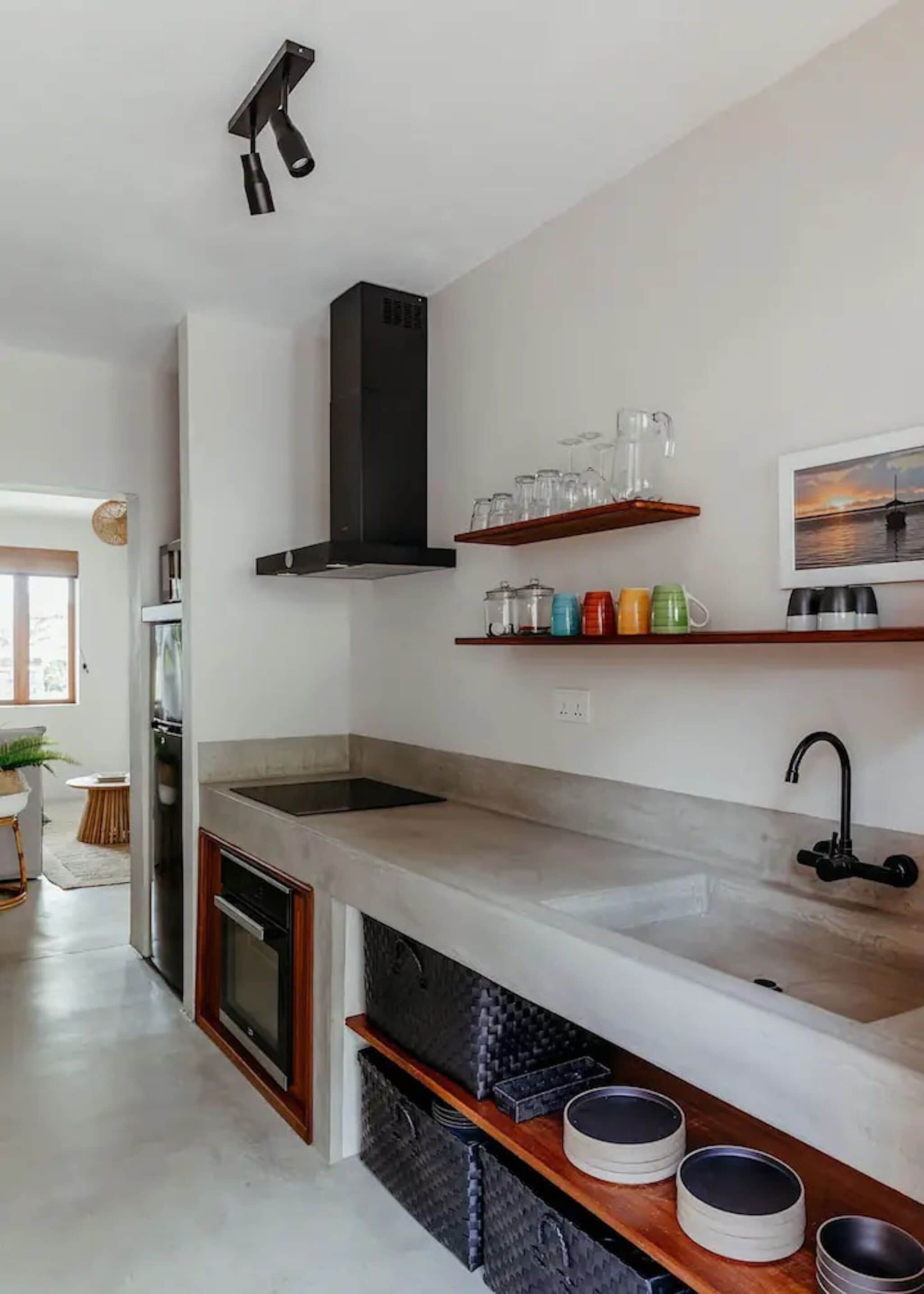 A modern kitchen with a central island, a built-in oven, and a stainless steel range hood.