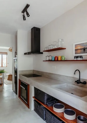 A modern kitchen with a central island, a built-in oven, and a stainless steel range hood. - Boutik Retreats (Le Morne)