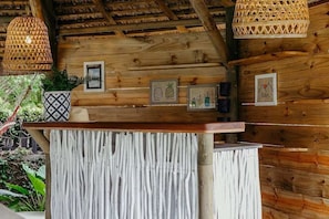 A wooden reception desk with a rustic design, surrounded by wooden walls and hanging woven light fixtures. - Boutik Retreats (Le Morne)