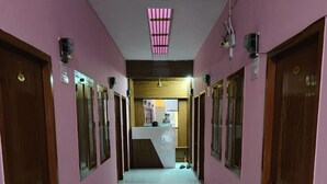 Pasillo de hotel con paredes rosas, puertas de madera y un mostrador de recepción central.