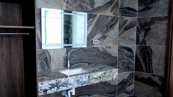 A bathroom with a marble sink, a mirror, and a window.