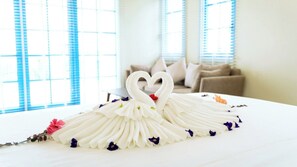 A bed with a decorative swan made of white fabric and flowers, in a room with large windows and a sofa. - Soleil Villa (Bai Chay)