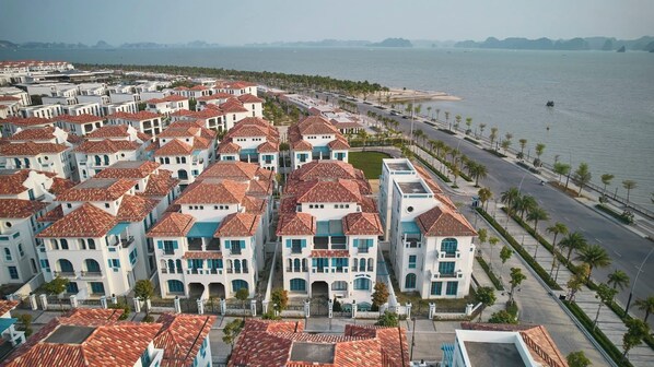 A coastal residential area with terracotta-tiled buildings, a beachfront promenade, and a marina. - Soleil Villa (Bai Chay)