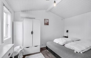 Ein Schlafzimmer mit Bett, Kleiderschrank, Schreibtisch und Fenster.