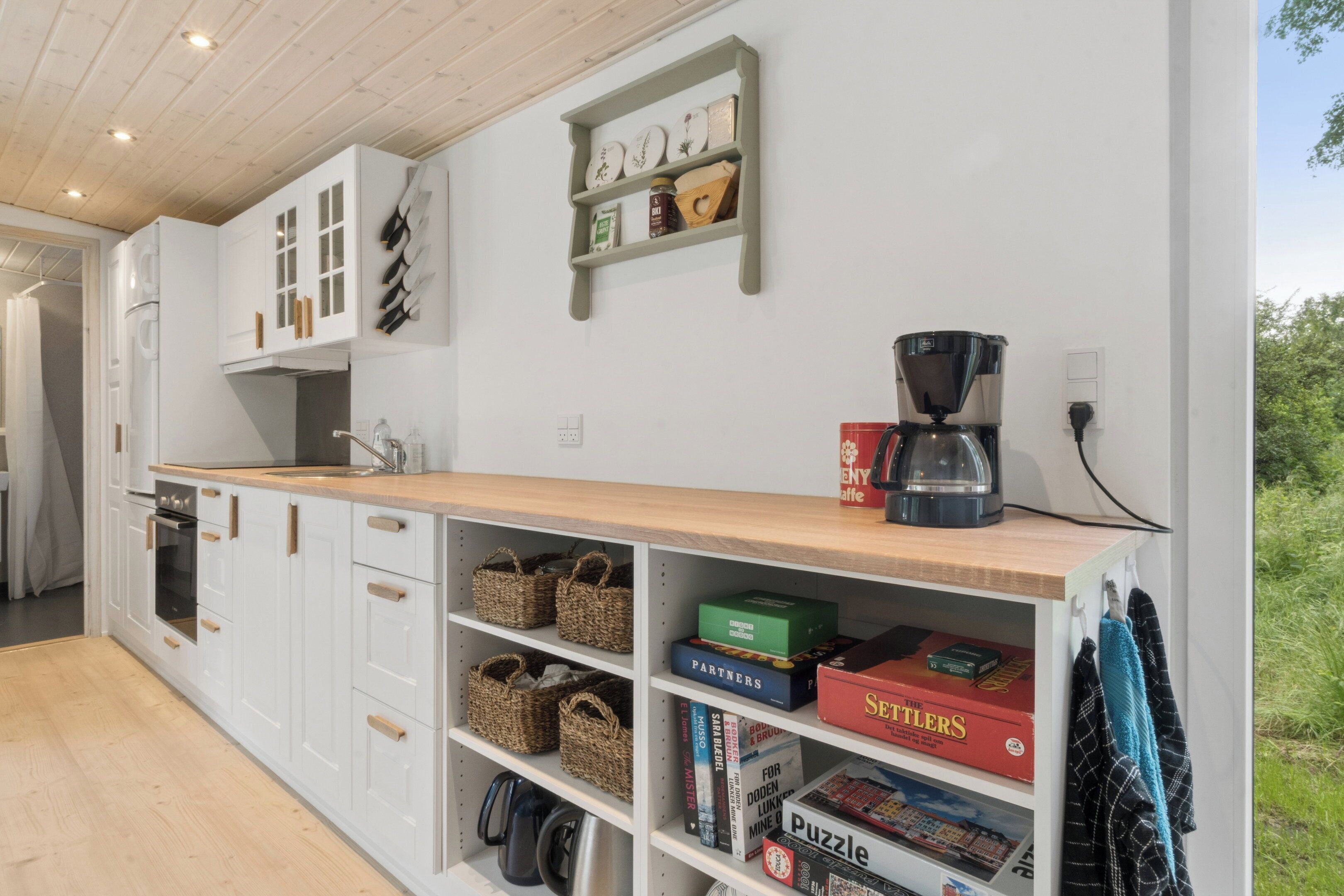 A modern kitchen with white cabinets, a wooden countertop, and various kitchen appliances.
