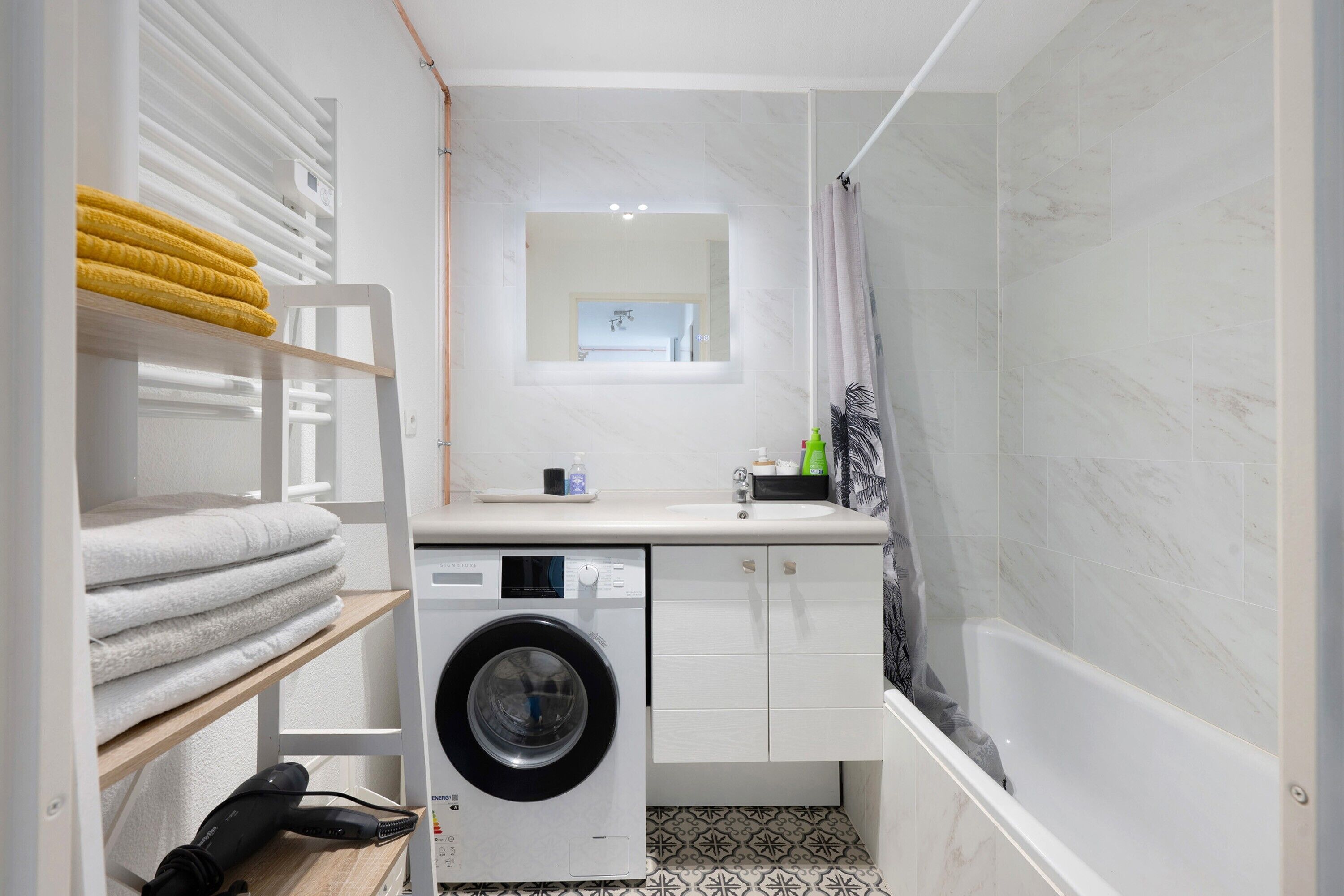 Une petite salle de bain équipée d’un lave-linge, d’un évier et d’une douche.