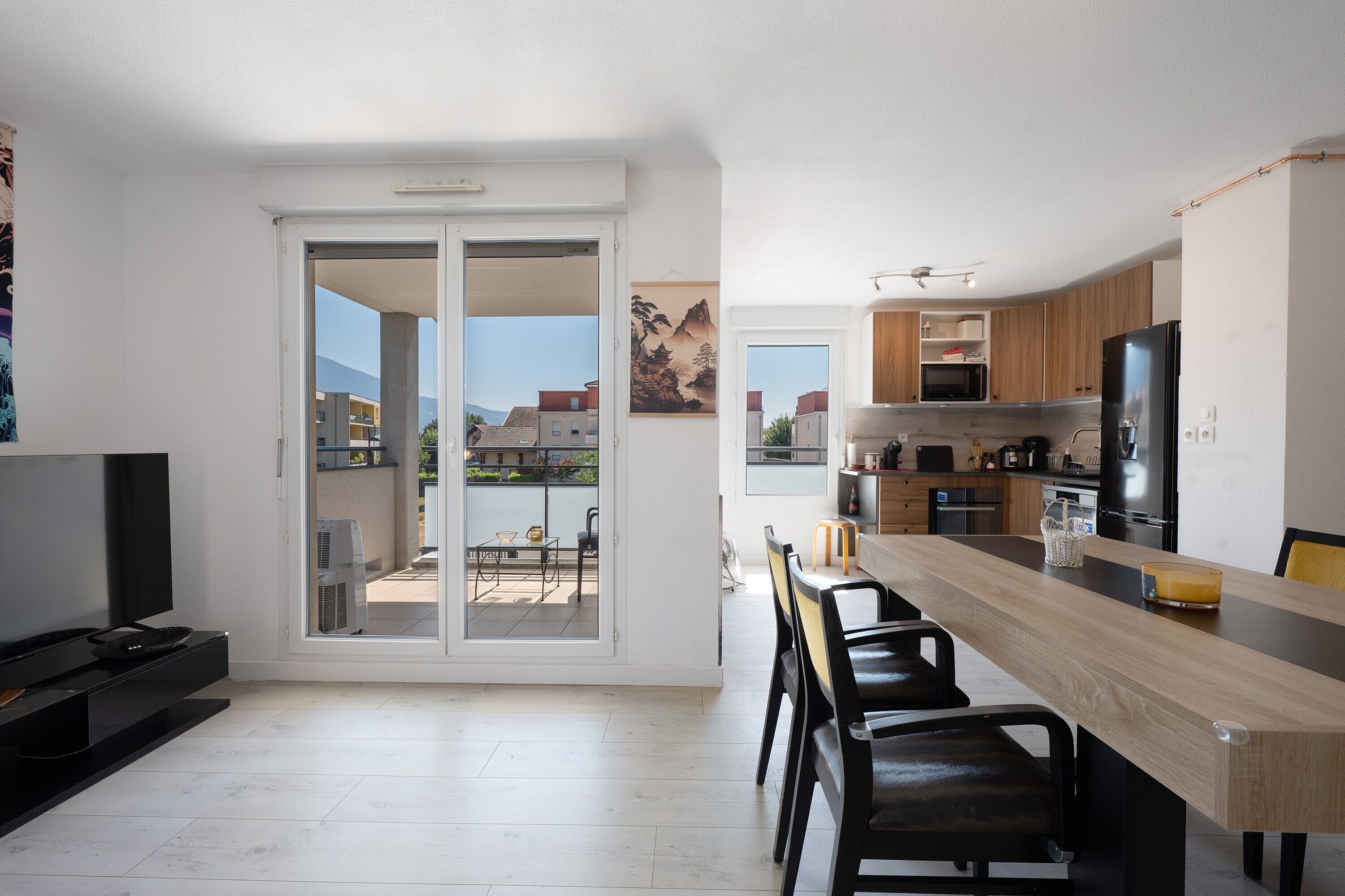 Eine moderne Küche mit einer großen Kochinsel, Essbereich und einer Glastür, die auf einen Balkon führt.
