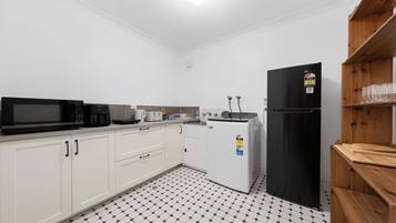 A compact kitchen with white cabinets, a black refrigerator, a microwave, a toaster, and a coffee maker.