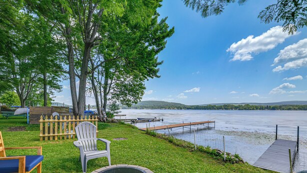 A lakeside deck with outdoor seating, a fire pit, and a dock extending into the water. - 2 Lamoka Lake Cottages w/ Views, Fire Pit & Dock (Bradford)