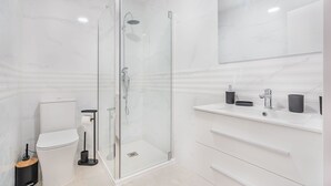 Een moderne badkamer met een douchecabine van glas, een toilet en een wastafel met spiegel.