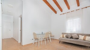 Een kamer met een eettafel, stoelen, een bank en een raam.
