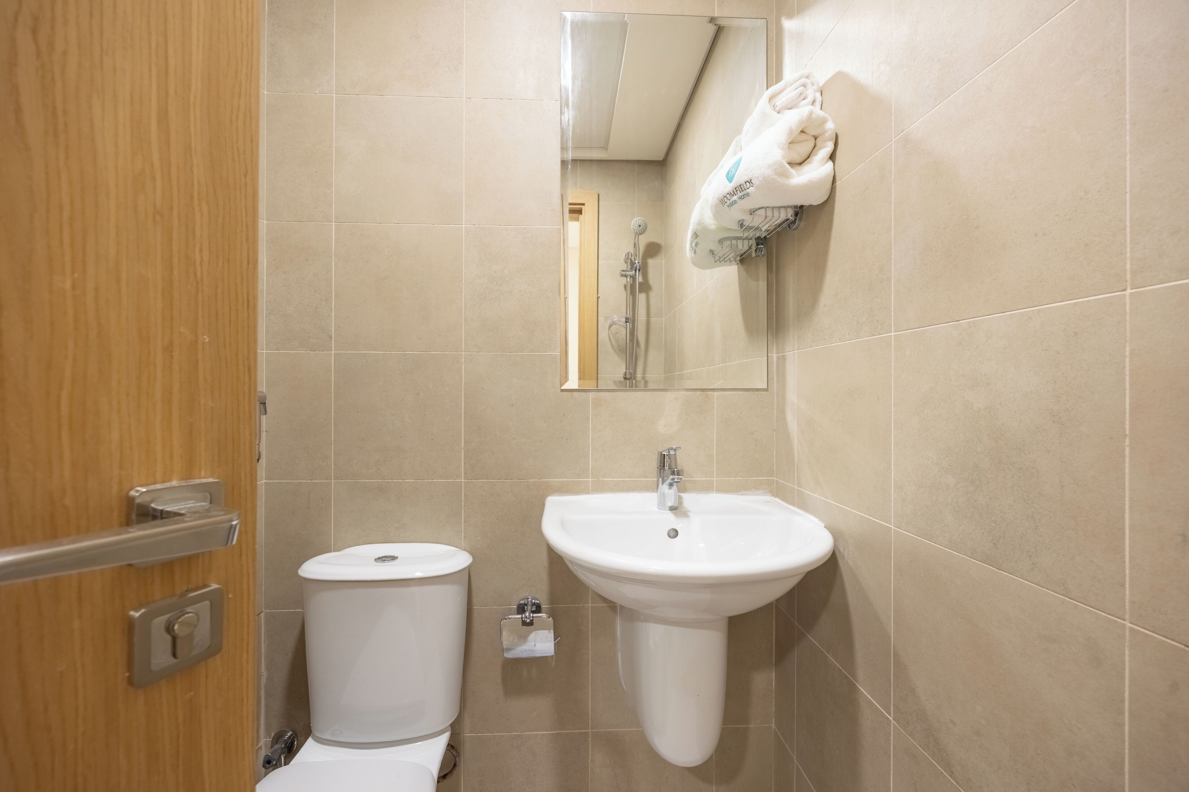 Une salle de bain équipée de toilettes, d’un lavabo, d’un miroir et d’un porte-serviettes.