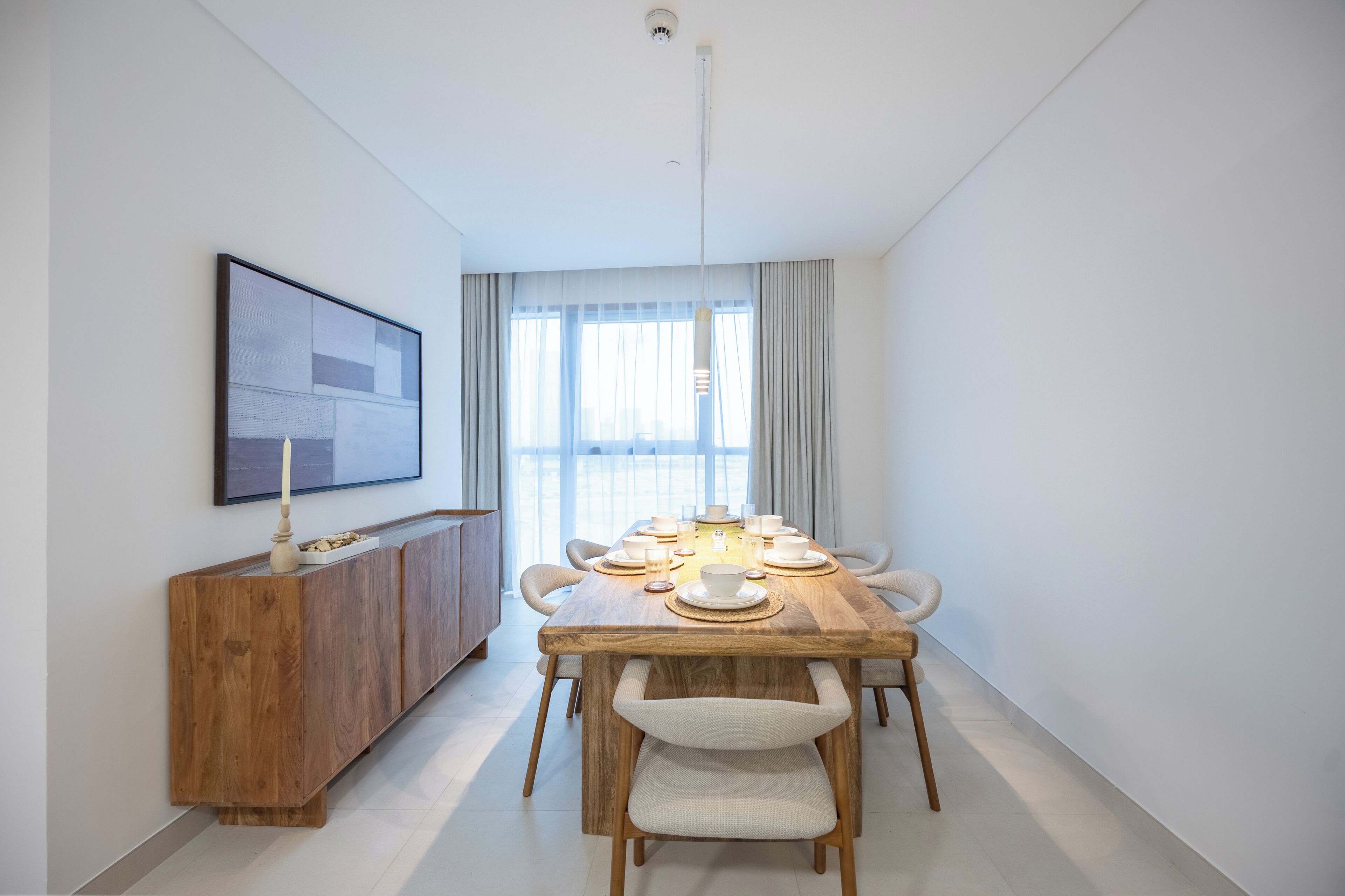 A dining area with a wooden table, white chairs, and a cabinet.