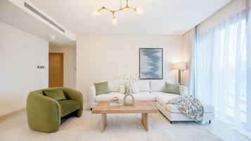 A modern living room with a sofa, a green armchair, a coffee table, and a chandelier.