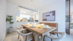 Un espace repas moderne avec une table en bois, des chaises blanches et une plante en pot.