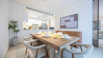 Un espace repas moderne avec une table en bois, des chaises blanches et une plante en pot.