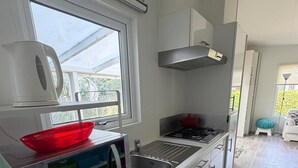 Ett modernt kök med ett fönster, rostfria vitvaror och utsikt över omgivningen.