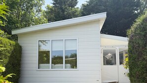 En liten, envåningsbyggnad med vit fasad, ett stort fönster och en dörr med ett fönster.