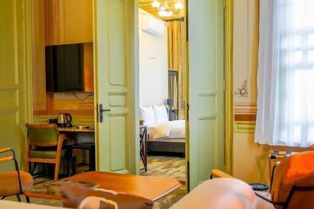 A hotel room with a bed, a desk, a television, and a seating area with chairs.
