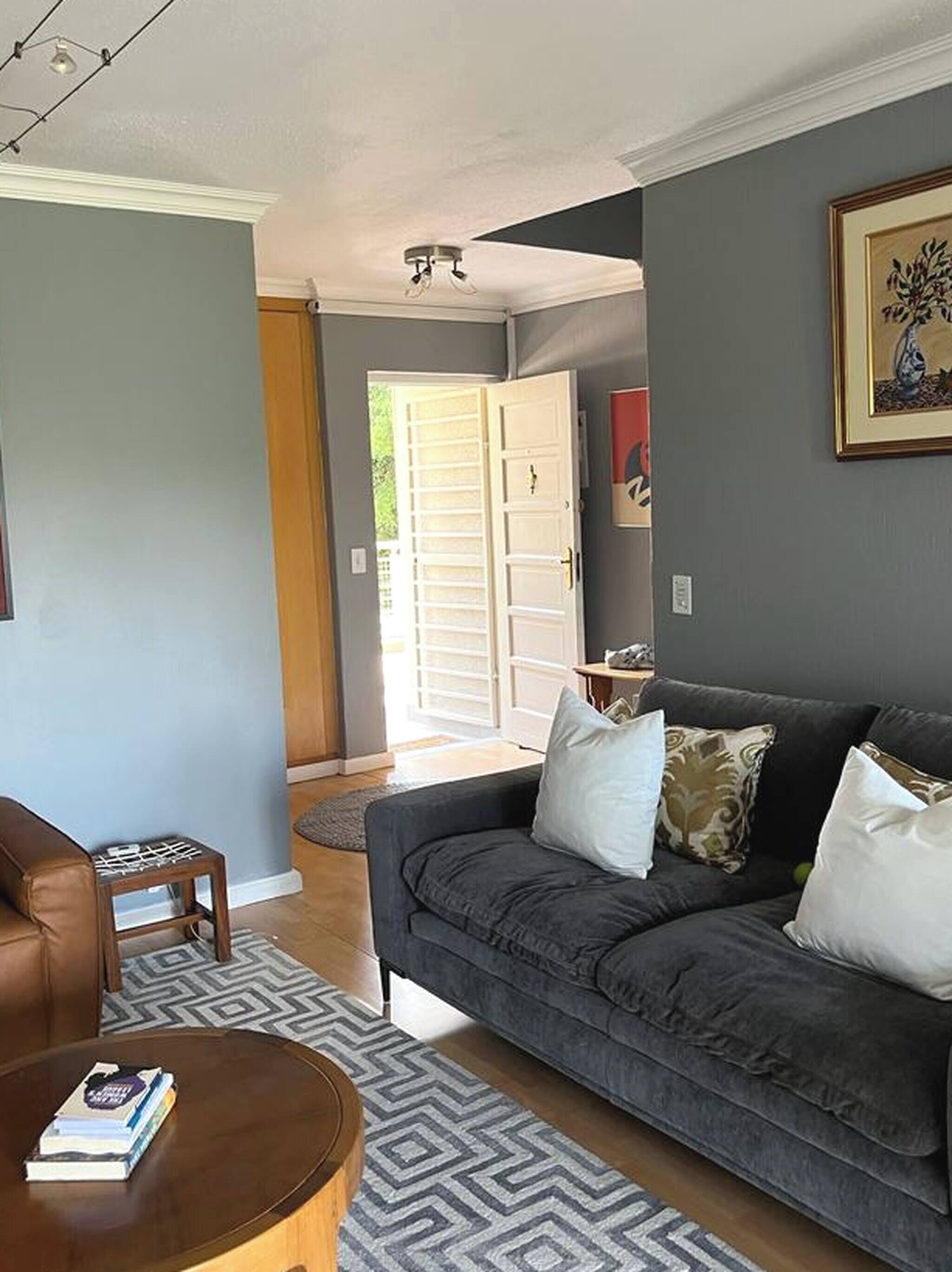 Una sala de estar con un sofá gris, una mesa de centro y una puerta que da a un balcón.