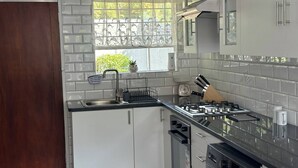 Eine moderne Küche mit weißen Schränken, einer Edelstahlspüle, einem Gasherd und einem Geschirrspüler.