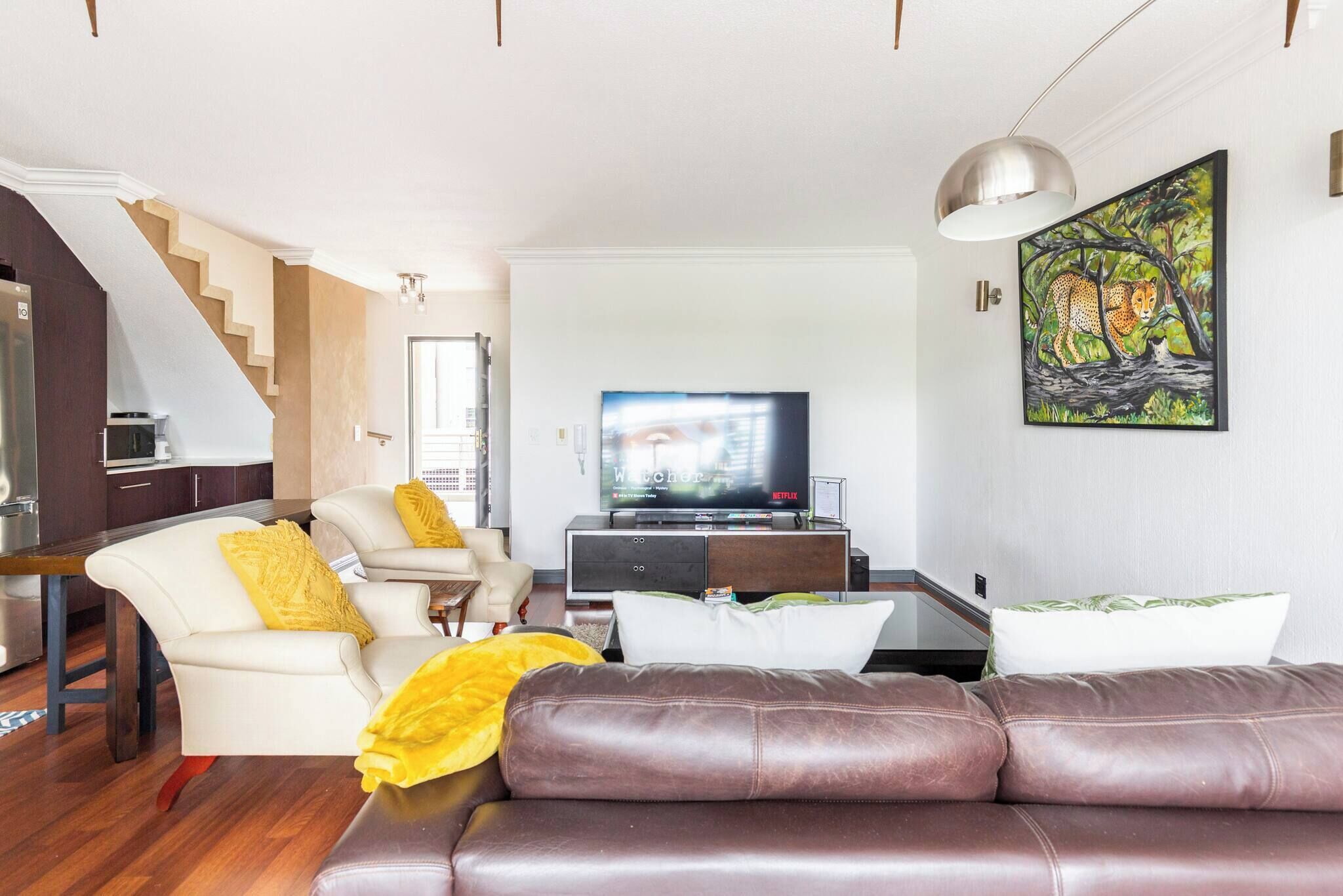 A living room with a sofa, a television, and a painting on the wall.