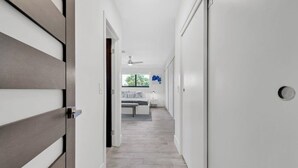 A hallway with a wooden door, a white wall, and a ceiling fan. - Villa Vivara, Luxury 7BR Retreat with Private Pool in Miami (North Miami Beach)