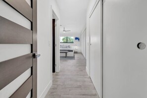 Ein Flur mit einer Holztür, einer weißen Wand und einem Deckenventilator.