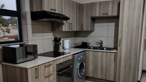 Eine moderne Küche mit Holzausstattung, integriertem Mikrowellenherd, einer Waschmaschine und einem Fenster mit Ausblick.