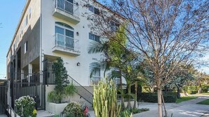 A multi-story residential building with balconies, a gated entrance, and a well-maintained garden. - Luxury 3 bedroom smart home condo in Sawtelle (Los Angeles)