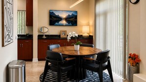 A modern dining area with a round table, chairs, a potted plant, and a painting on the wall. - Luxury 3 bedroom smart home condo in Sawtelle (Los Angeles)